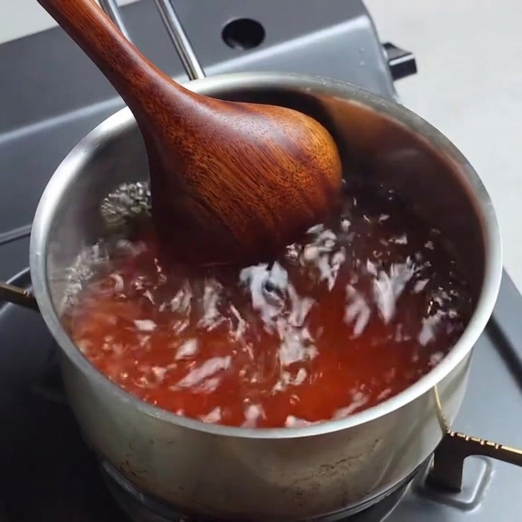 Caldo de ramen condimentado burbujeando en una cacerola mientras se revuelve.