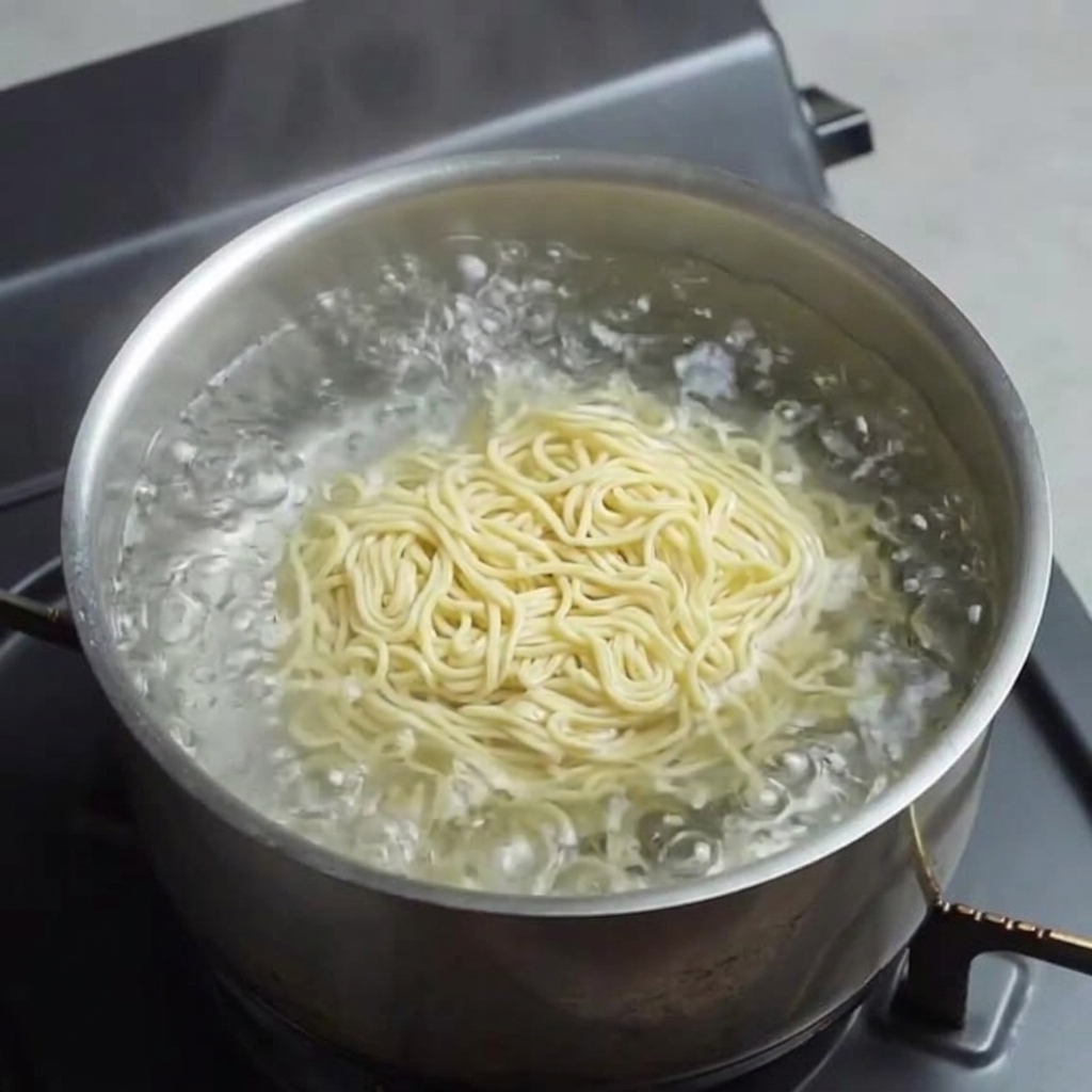 Fideos amarillos y frescos de ramen cociéndose en agua hirviendo.