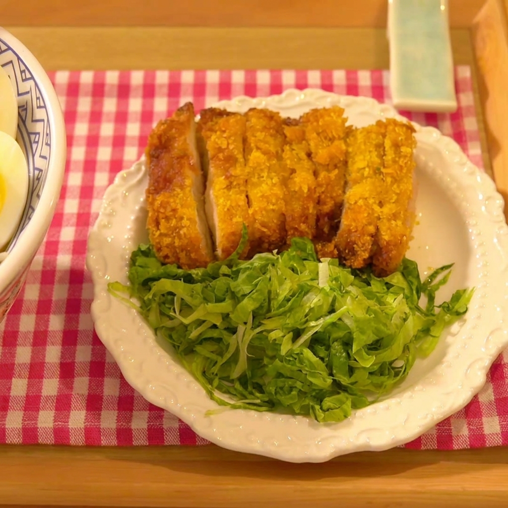 El filete de pollo siendo presionado firmemente sobre una base de pan rallado panko.