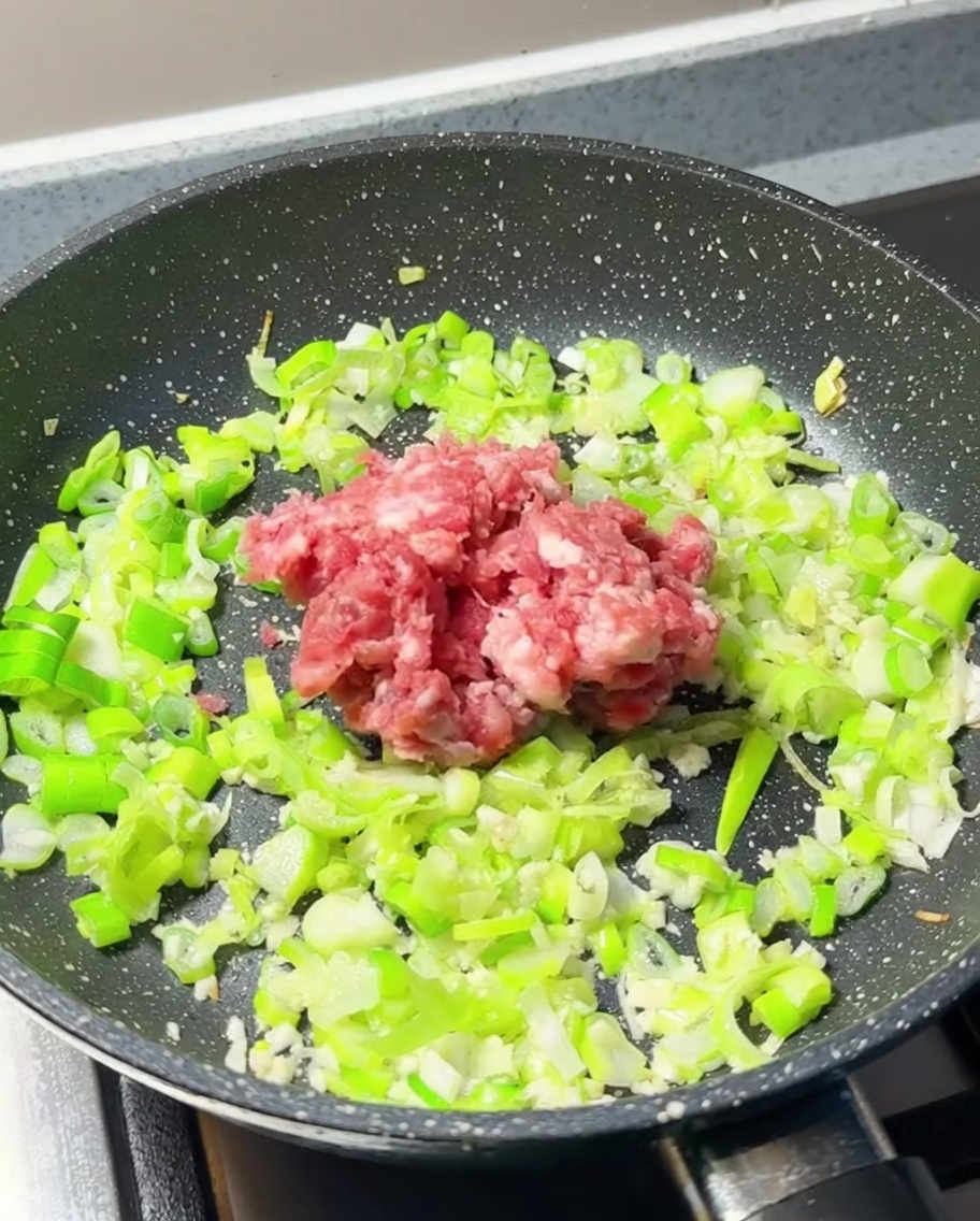 Carne picada fresca añadida al centro de la sartén con los aromáticos.