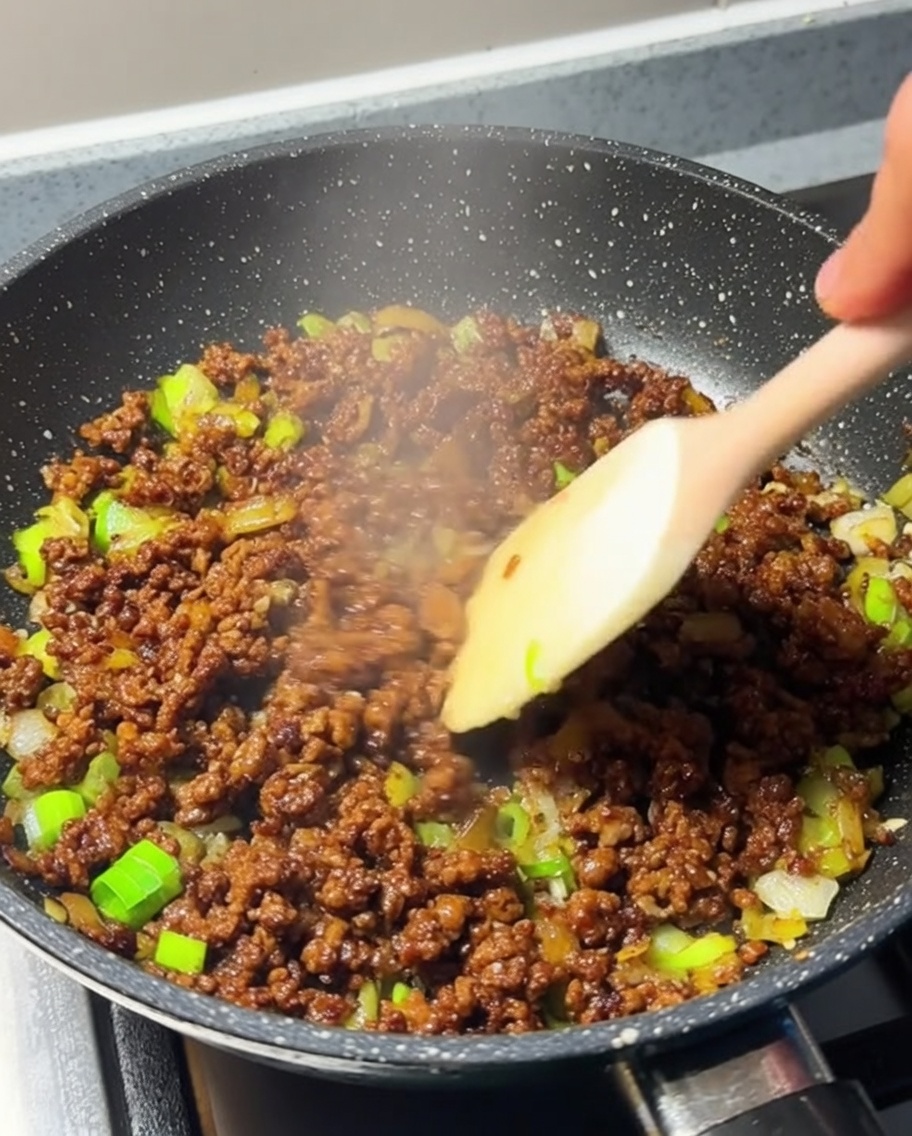 Carne picada siendo removida en la sartén, ahora bien dorada.