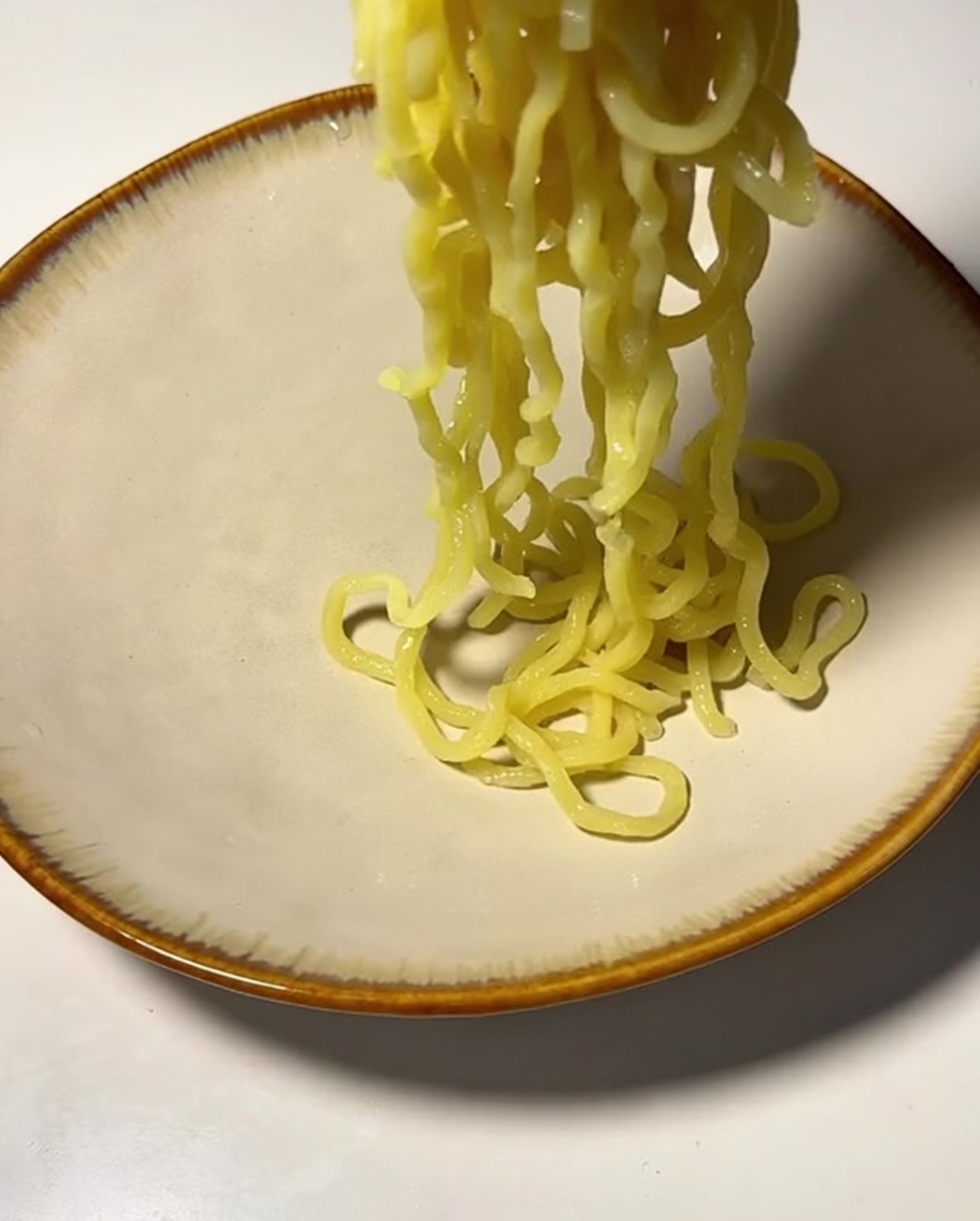 Fideos cocidos siendo colocados en un tazón.
