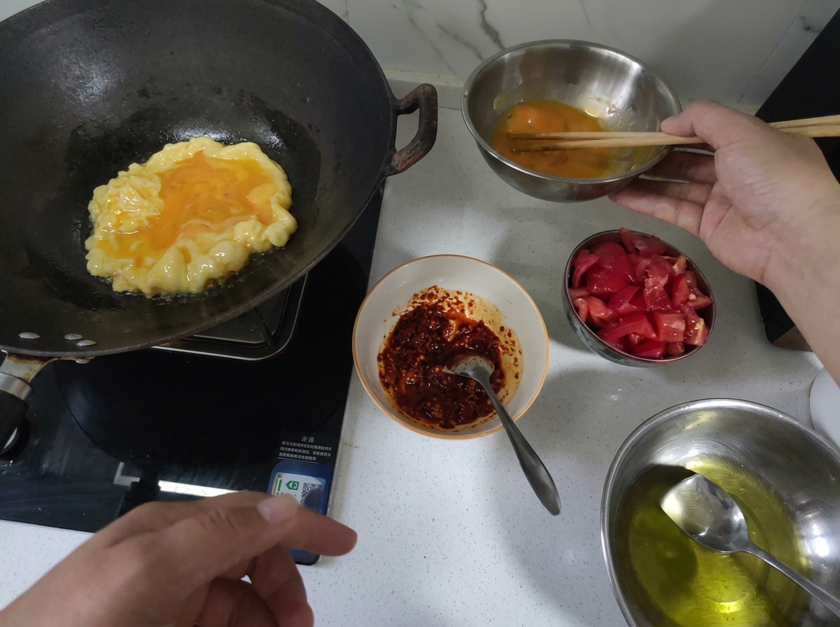 Huevos siendo revueltos en un wok caliente hasta quedar esponjosos.