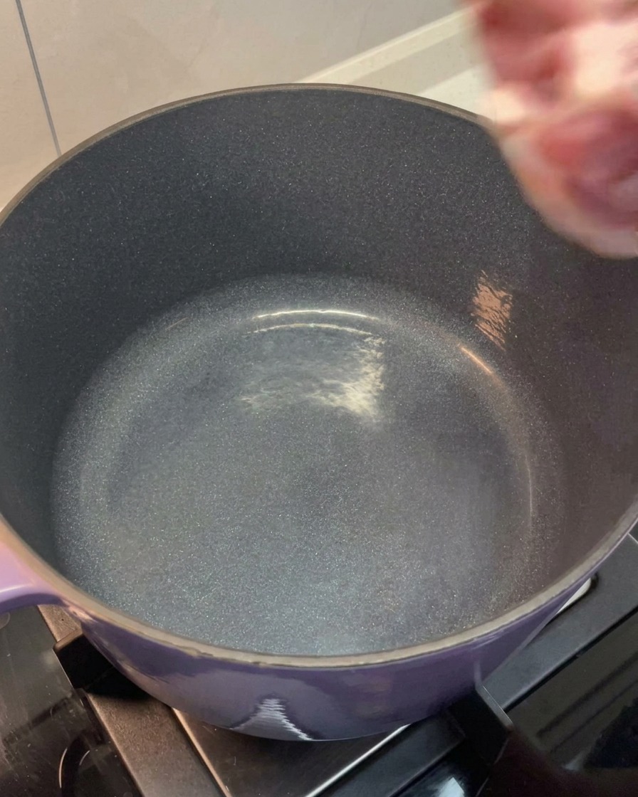 La carne y los huesos enjuagados colocados en una olla grande.