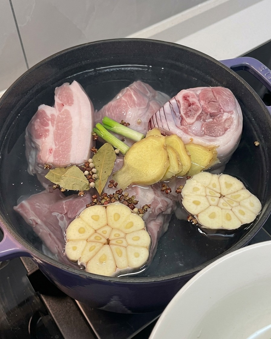 Carne en la olla con cebolla, ajo, jengibre, cebolleta y especias enteras.