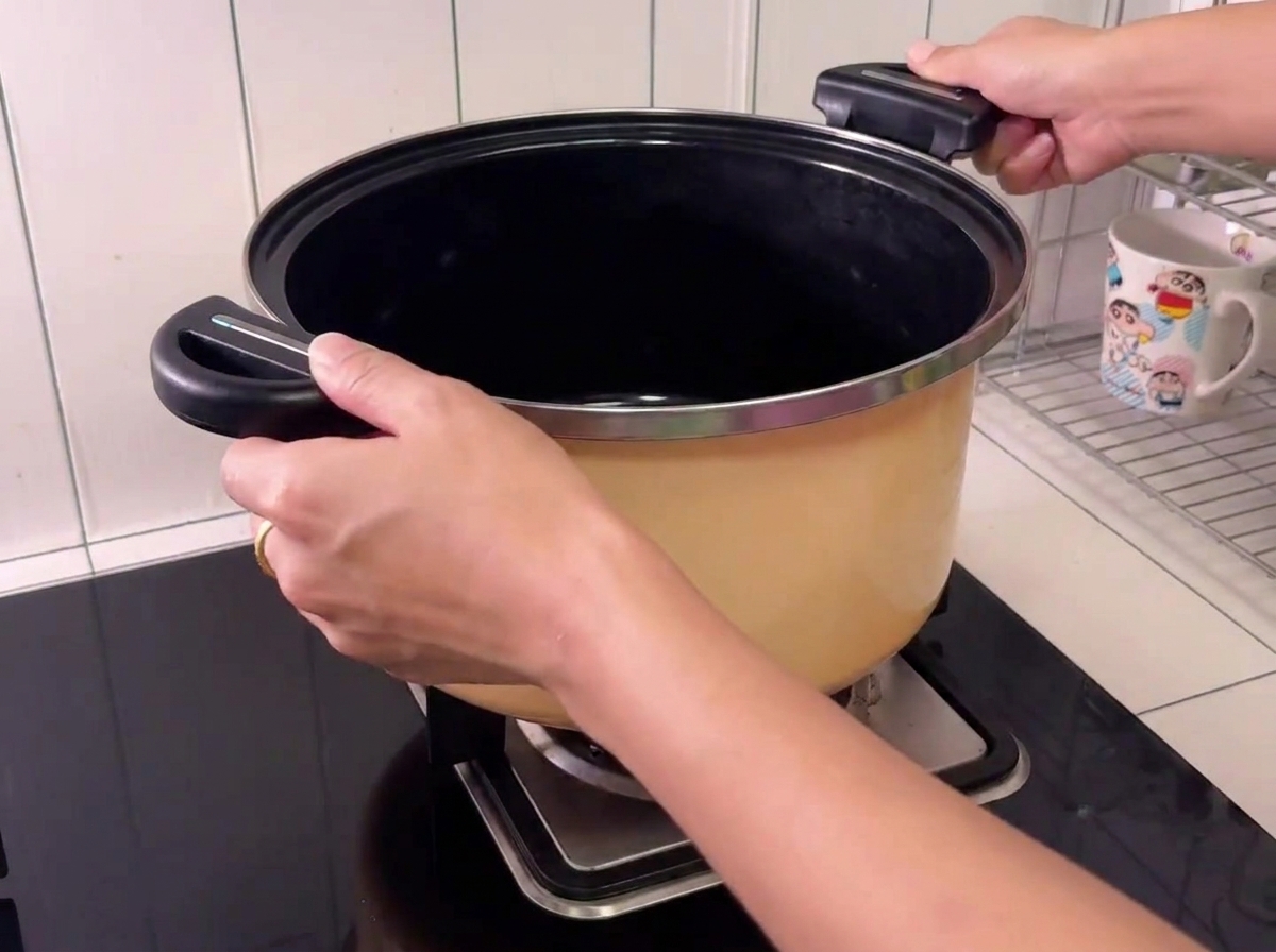 Piezas de cerdo dentro de una olla grande con una botella de vino de cocina siendo añadida.