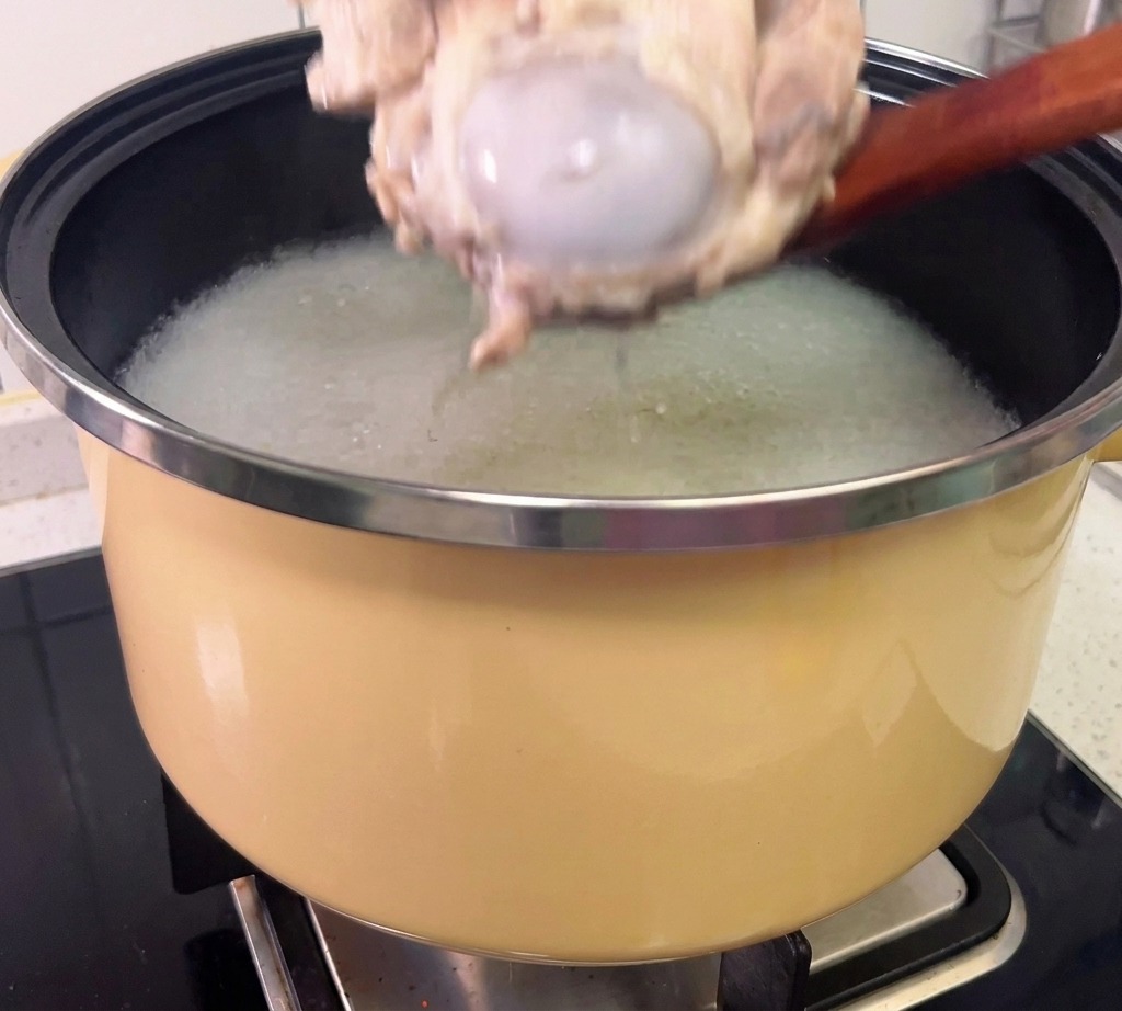 Carne siendo desmenuzada de los huesos de cerdo cocidos usando guantes protectores.