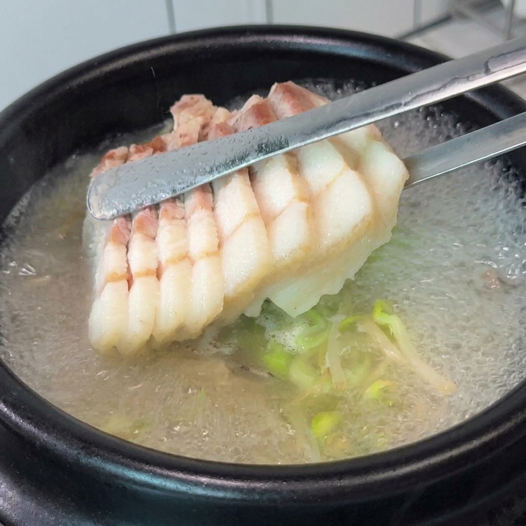 Rodajas de panceta y cebollino picado siendo añadidos a una olla de sopa hirviendo.