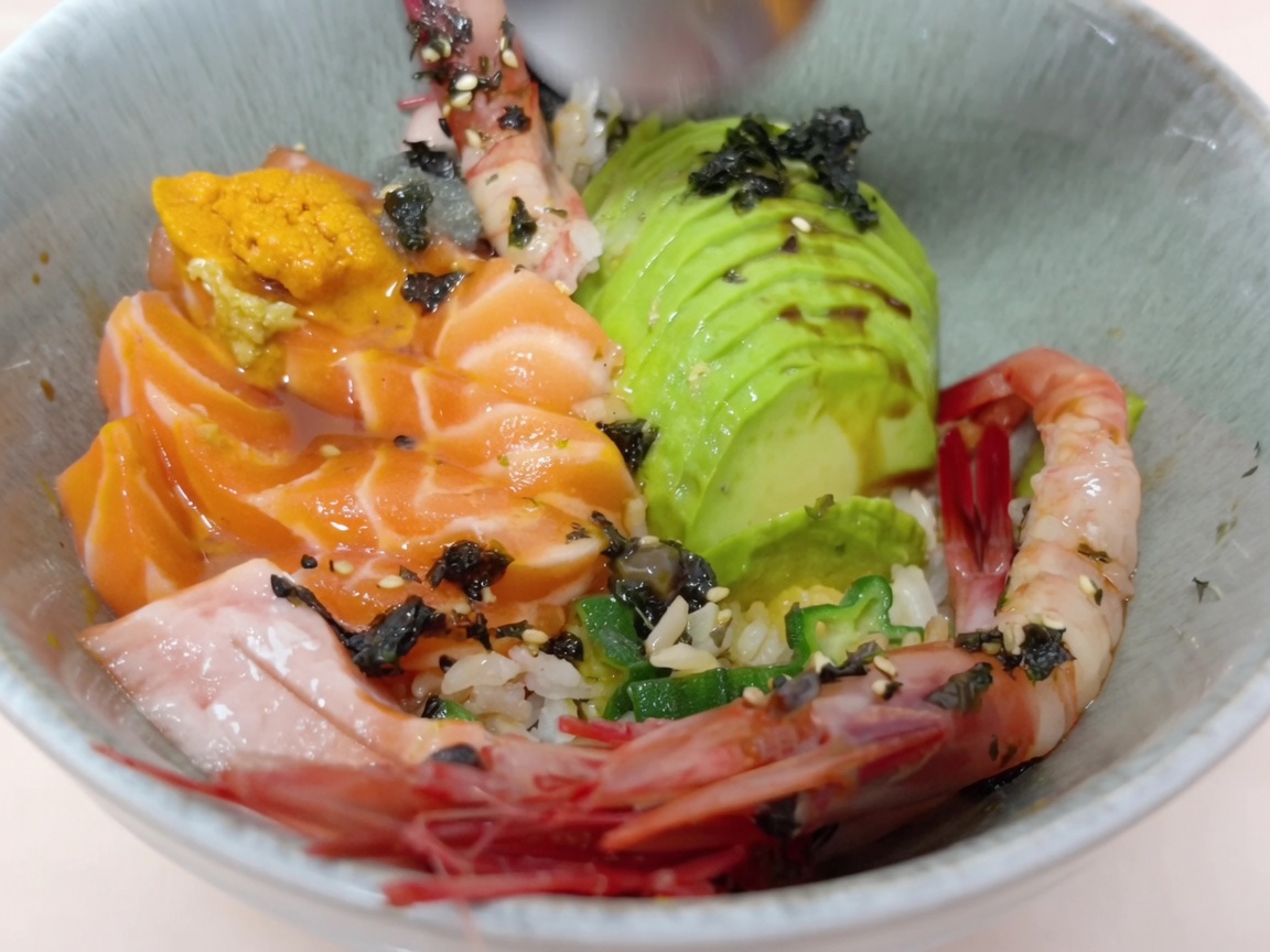 Erizo de mar fresco siendo añadido cuidadosamente al tazón de arroz con una cuchara.