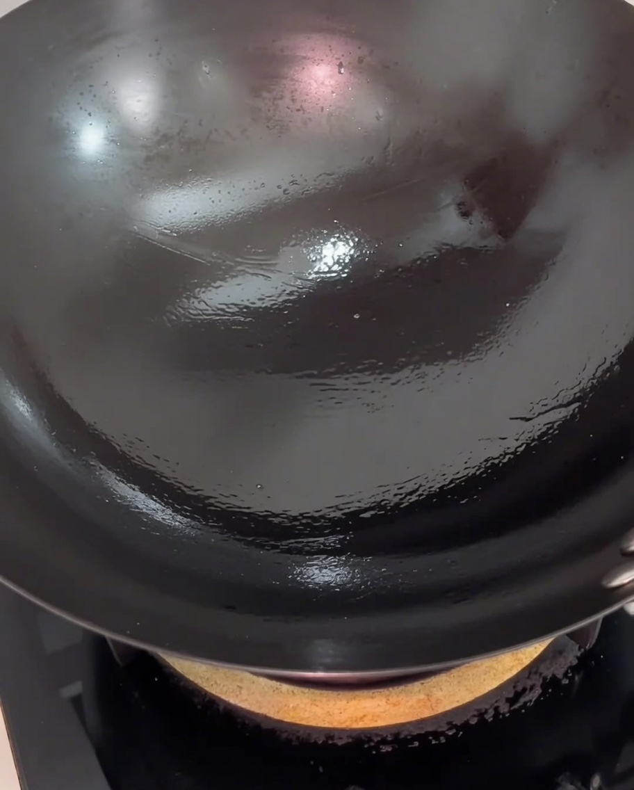 La panceta salteándose en el wok, mostrando un dorado ligero en la superficie.