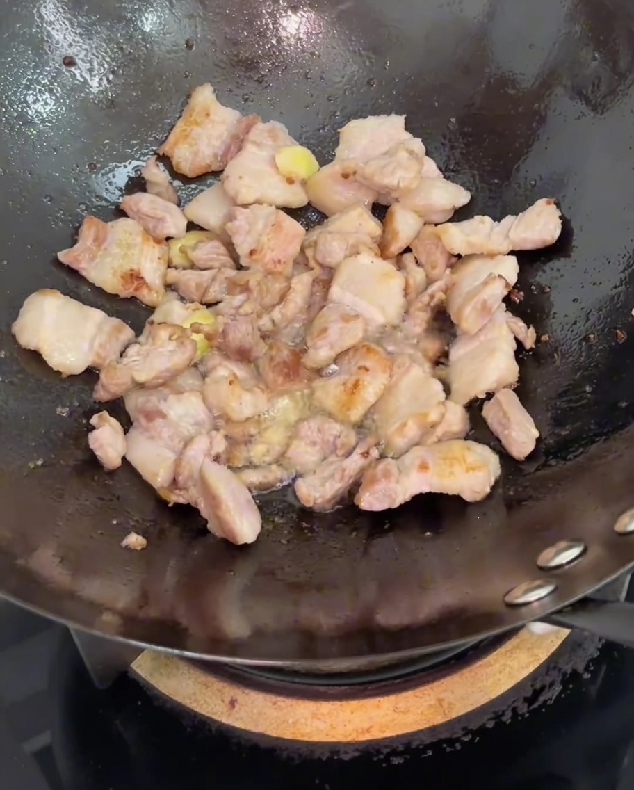 Salsa de soja vertida sobre el cerdo y el jengibre en el wok.