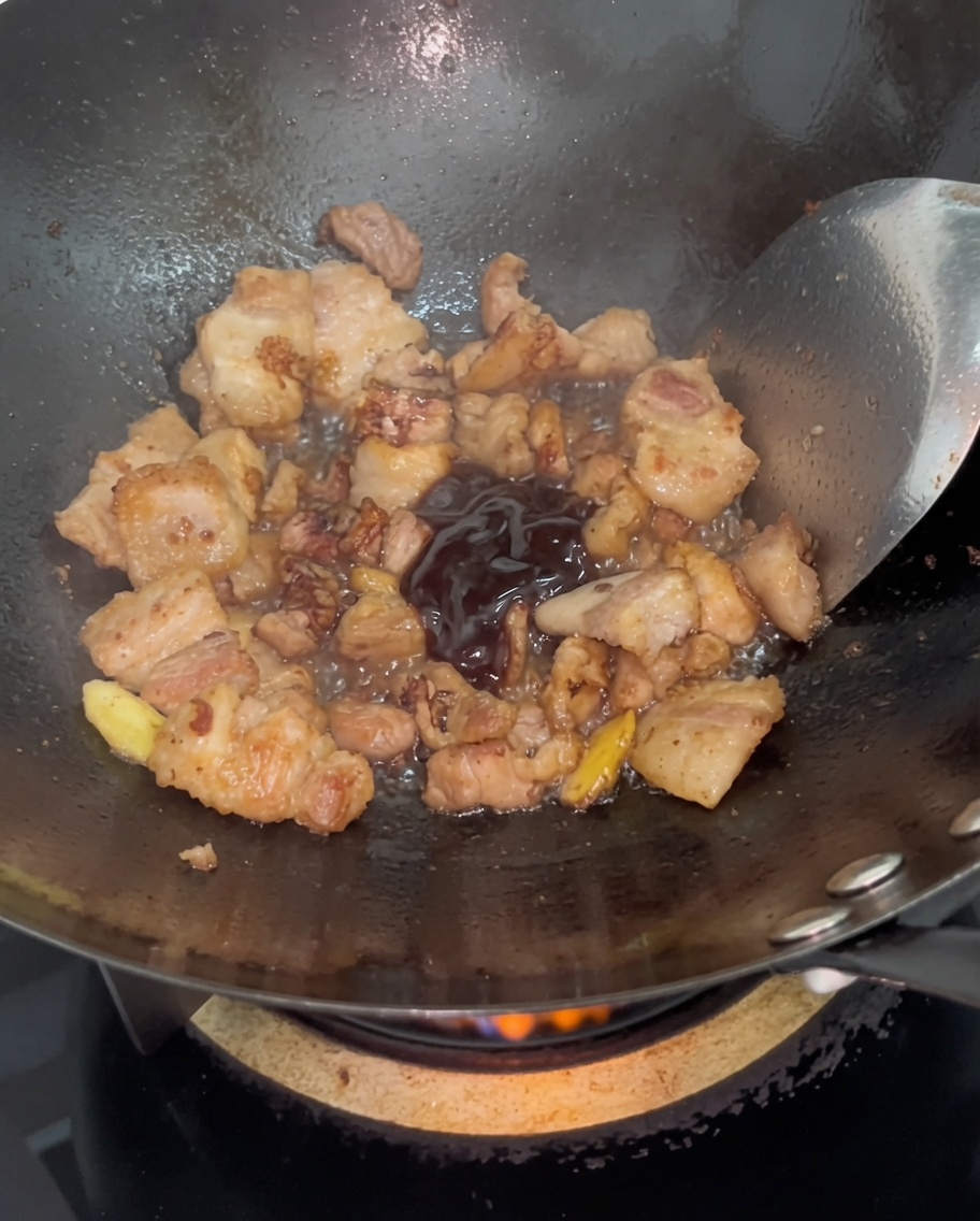 Salsa de ostra oscura siendo integrada con el cerdo dorado en el wok.