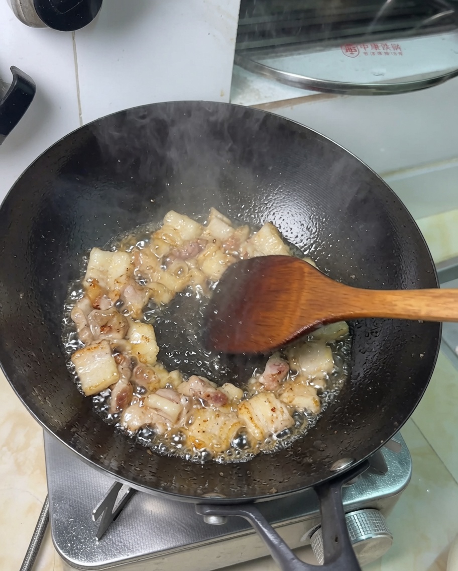 Trozos de panceta friéndose en su propia grasa en un wok.