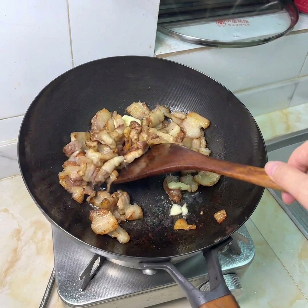 Dientes de ajo machacados salteándose con trozos de panceta dorada.