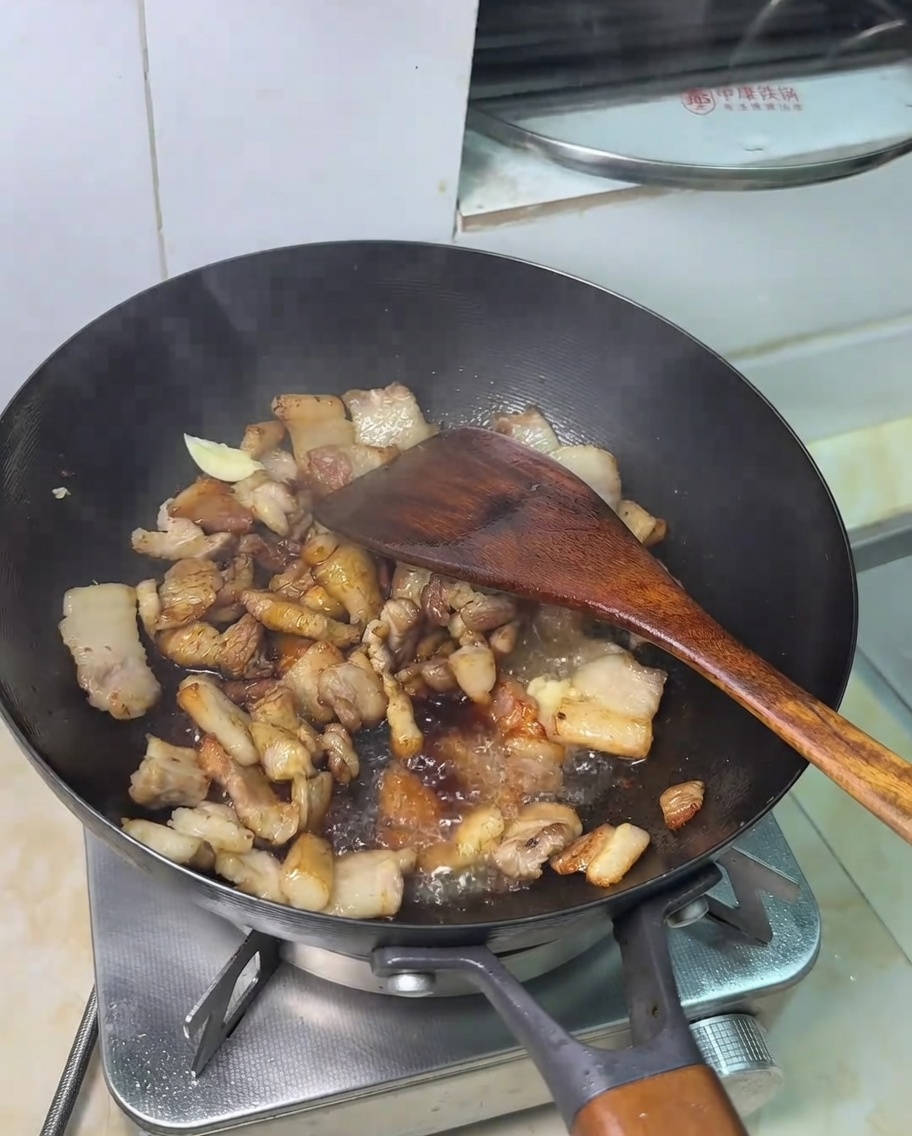 Una cucharadita de azúcar siendo añadida a la mezcla de carne y soja.