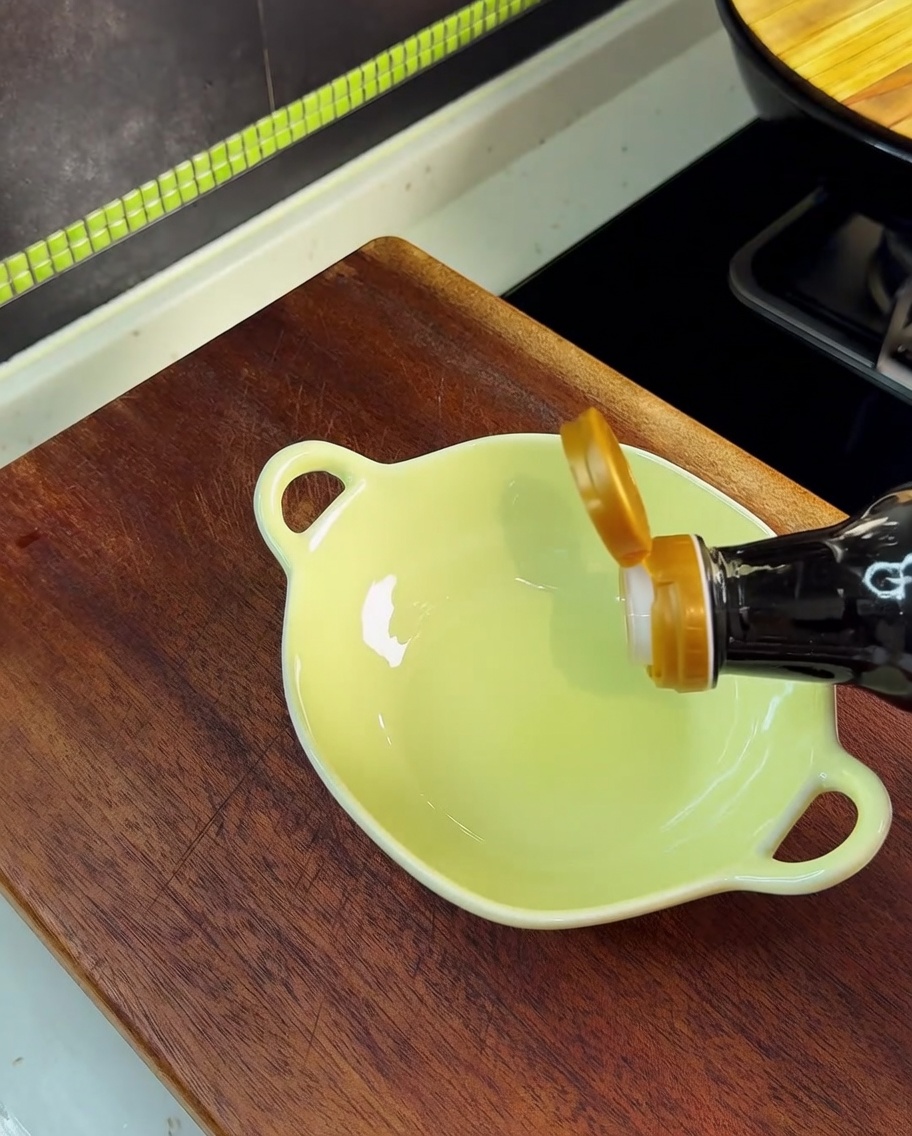 Salsa de soja siendo vertida en un pequeño cuenco amarillo que contiene sal, MSG y azúcar.