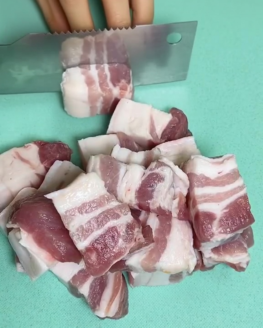 Trozos de panceta cruda en una olla con agua fría, jengibre y vino de cocina.