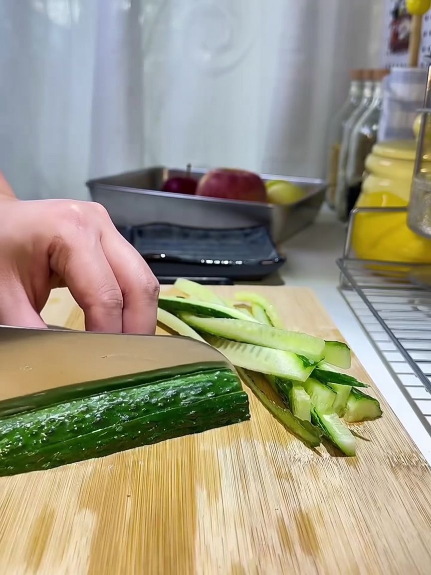 Tiras finas de pepino dispuestas cuidadosamente sobre una tabla de cortar de madera.