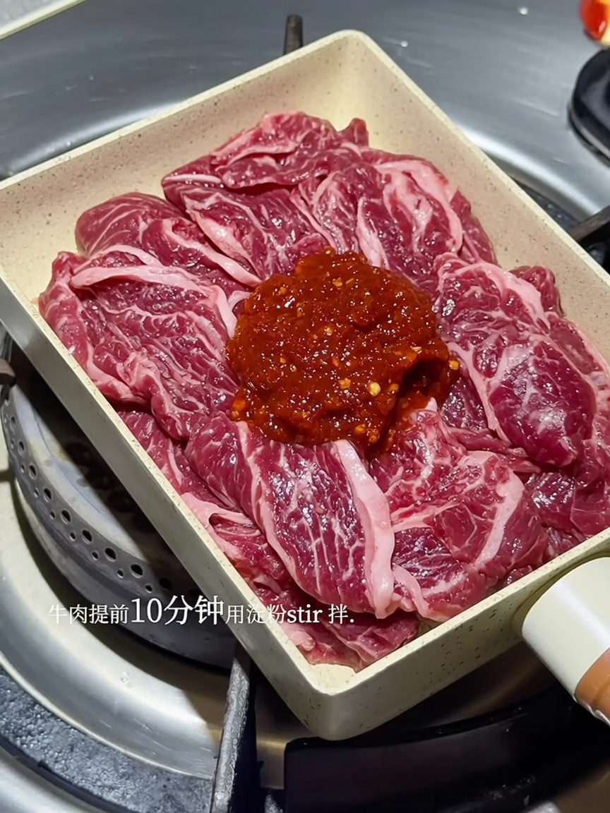 Tiras de ternera chisporroteando en una sartén, cubiertas con una rica salsa roja coreana picante.