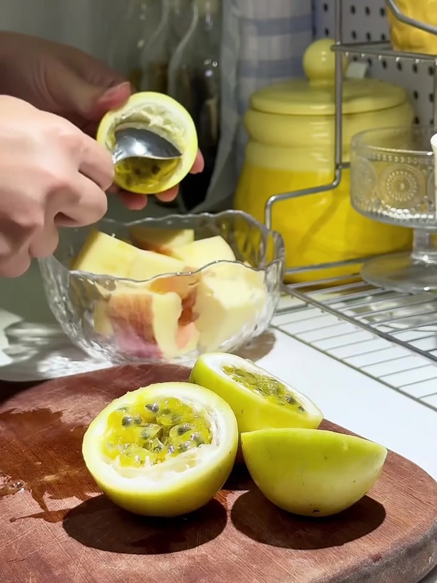Pulpa fresca de maracuyá siendo vertida sobre los gajos de manzana en un bol de cristal.