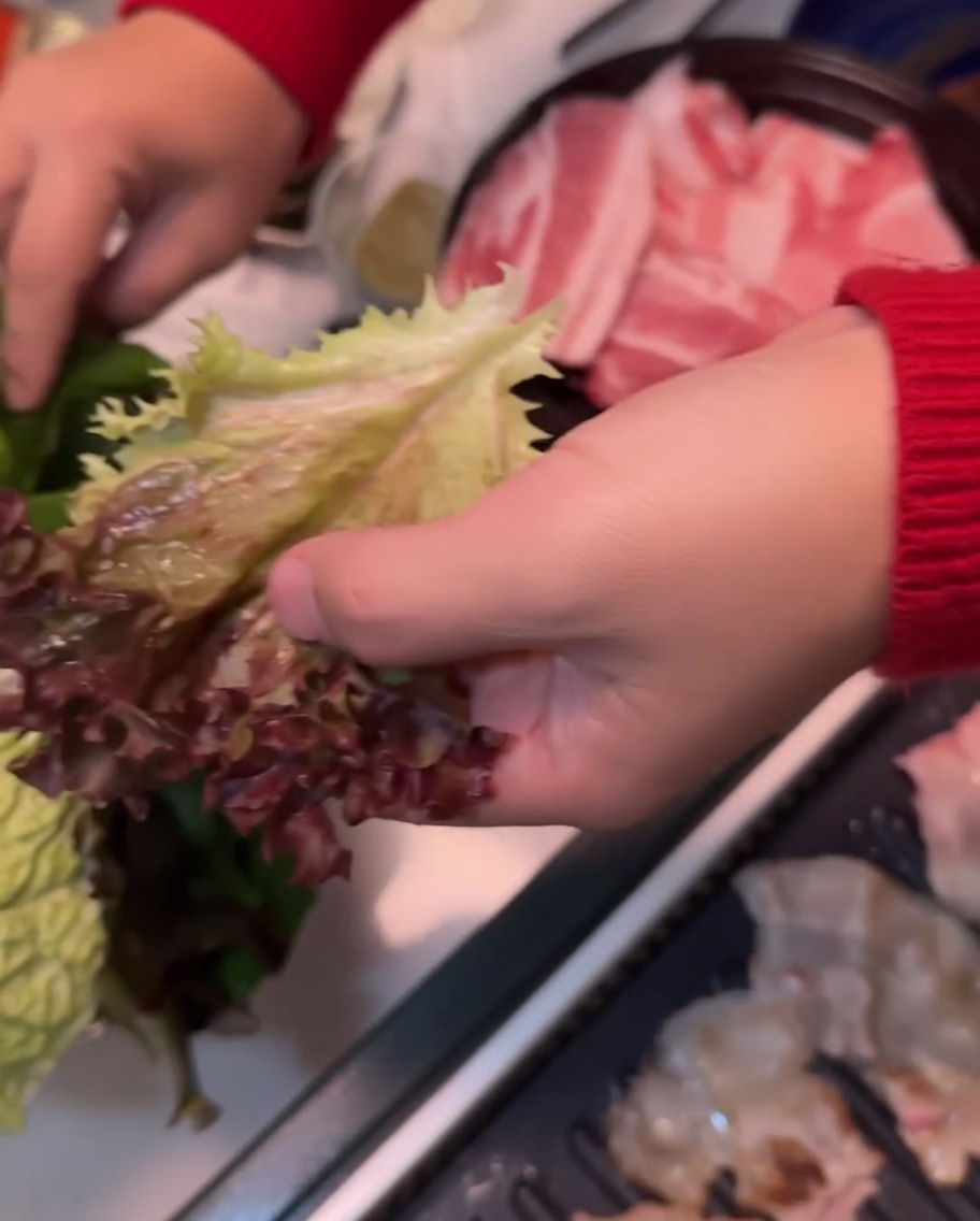 Una hoja de lechuga siendo colocada sobre una hoja de perilla, lista para armar.