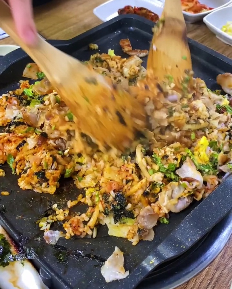 Arroz frito salteándose con los trozos de carne en la plancha.