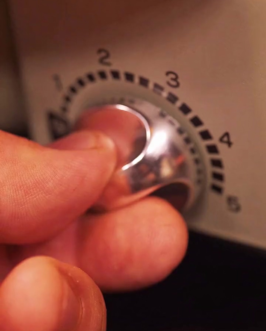 Mano ajustando el selector de temperatura de una parrilla eléctrica.