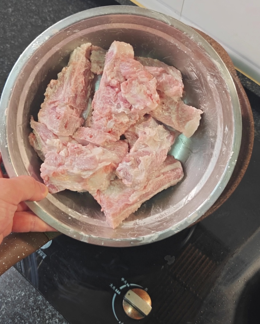 Costillas de cerdo crudas cubiertas con almidón rojo en un tazón.