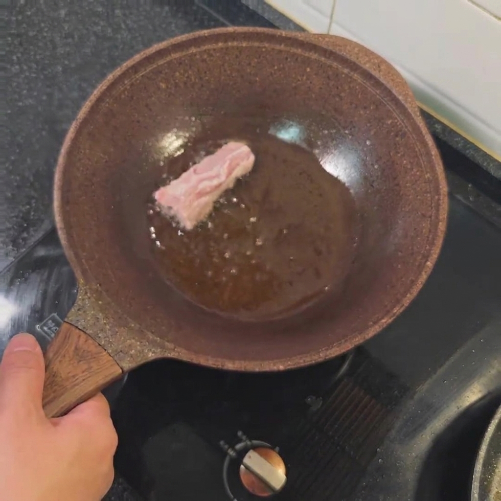 Costillas de cerdo friéndose en aceite caliente hasta dorarse.