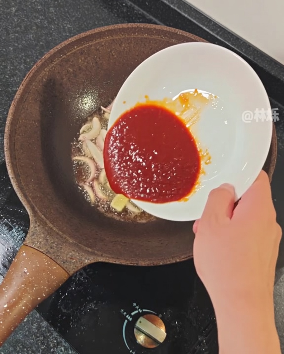 Salsa picante siendo vertida en la sartén con los aromáticos.