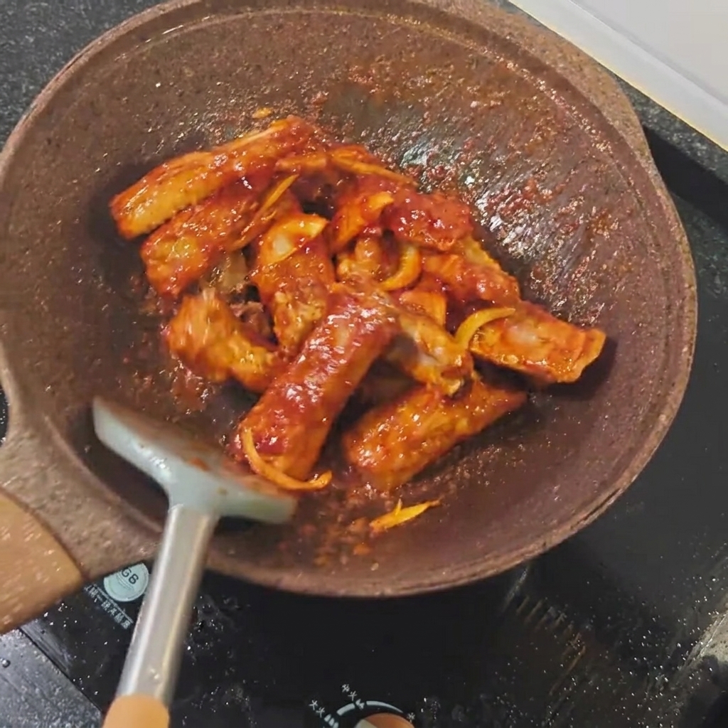 Salsa de soja clara siendo vertida sobre las costillas en la sartén.
