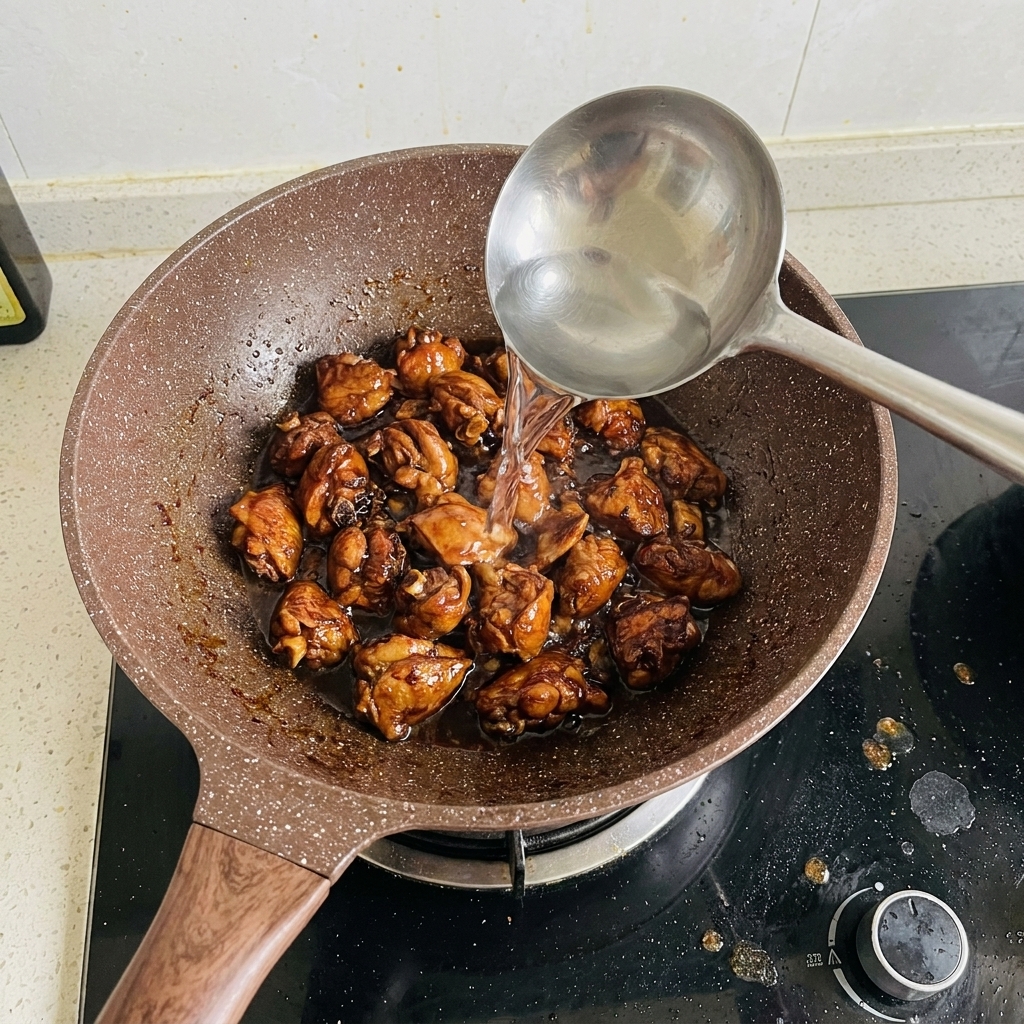 Agua siendo vertida con un cucharón en la sartén con las costillas.