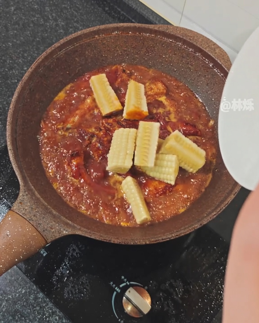Trozos de maíz fresco añadidos a la sartén con las costillas.