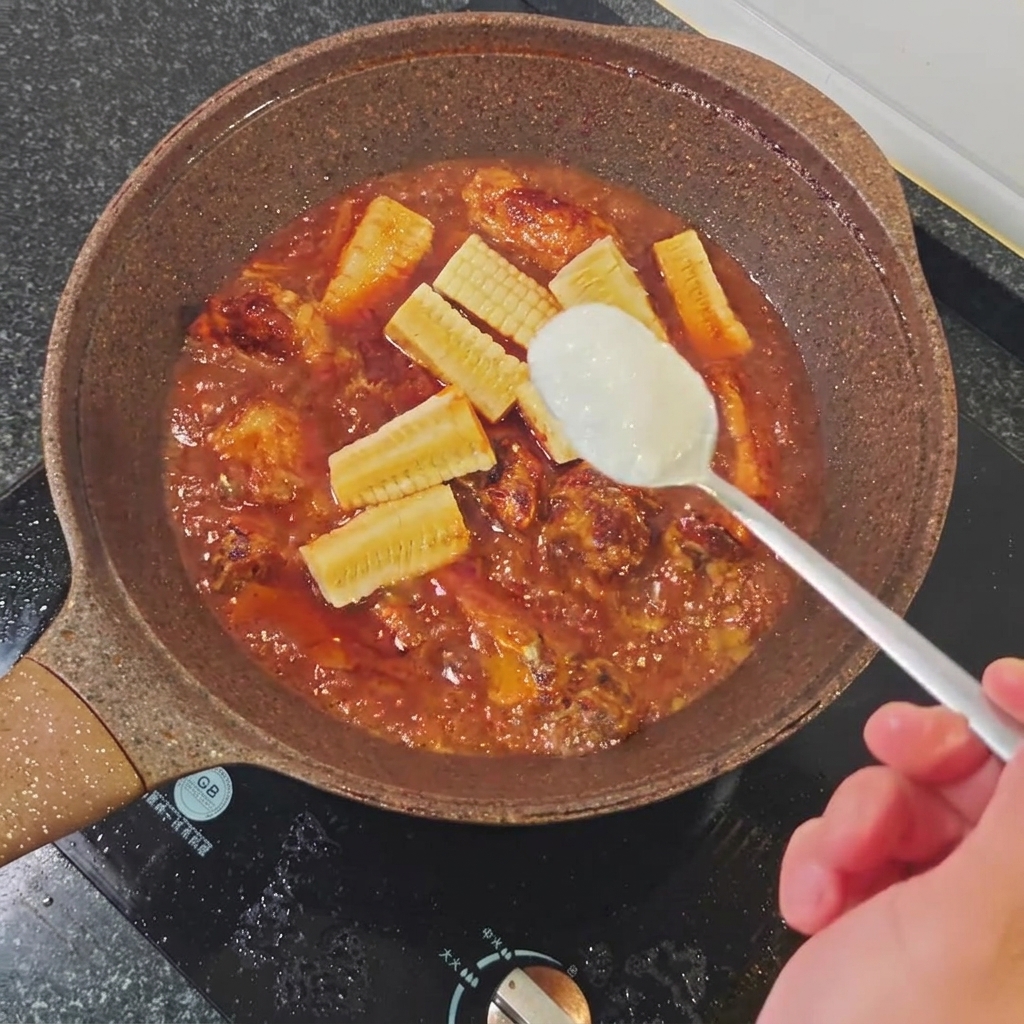 Una cucharada de azúcar blanco siendo añadida a la sartén.