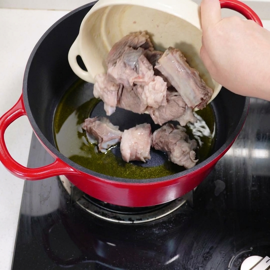 Costillas de cerdo blanqueadas salteándose en una olla con aceite caliente hasta que se doren.