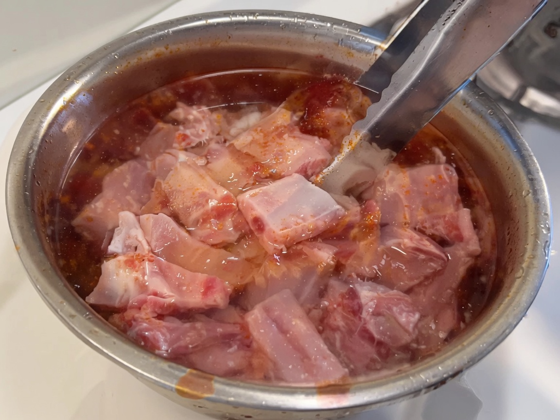 Costillas de cerdo crudas y frescas sumergidas en un tazón con agua limpia.