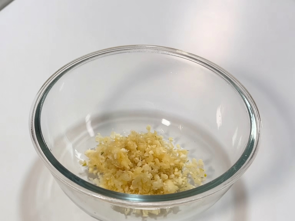 Tazón de vidrio que contiene la mezcla de pasta de chile, salsa de soya y aromáticos para la salsa de guisar.