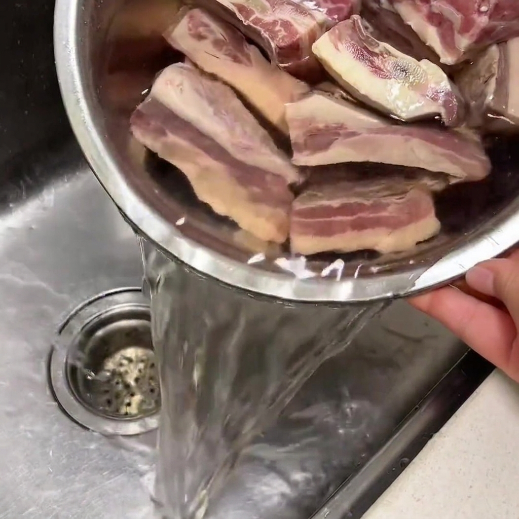Costillas de res remojándose en un bol con agua fría en el fregadero.