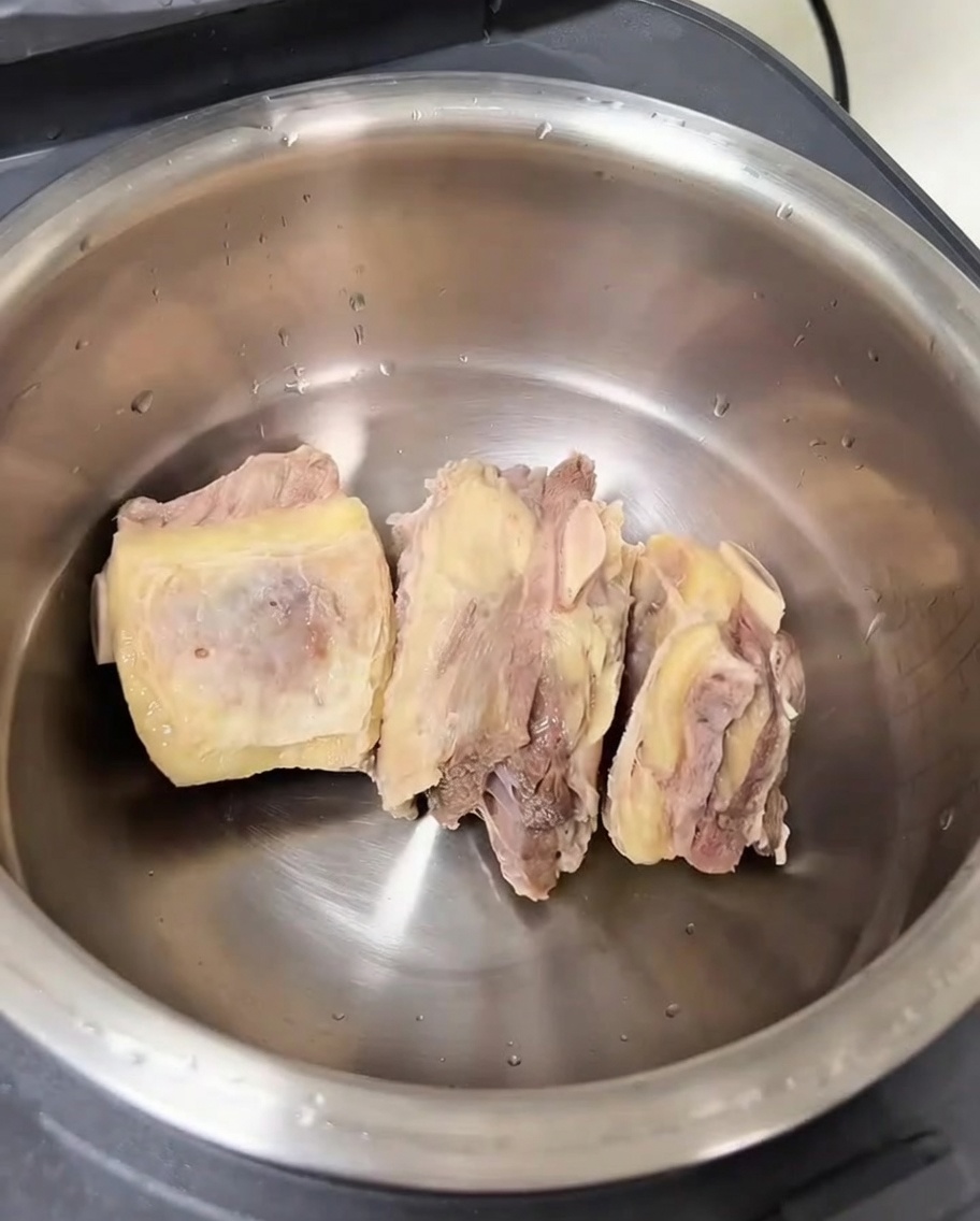 La olla interior de la arrocera con costillas limpias y aromáticos.