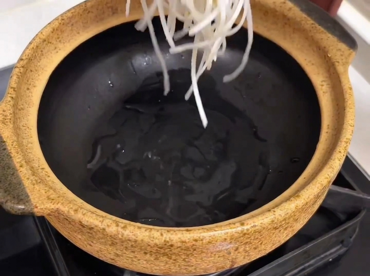 Olla de servicio con fideos de vidrio, costillas y trozos de rábano.