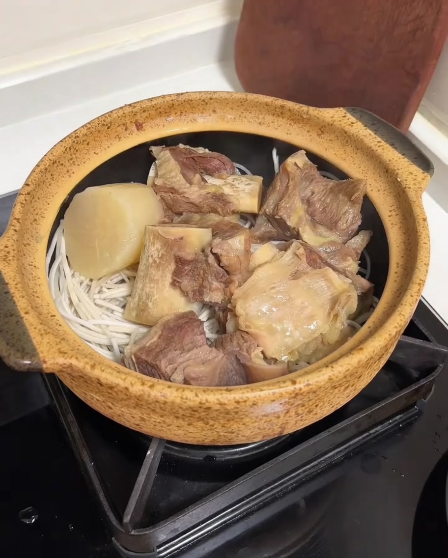 Caldo de res siendo vertido desde la arrocera al recipiente de servicio.