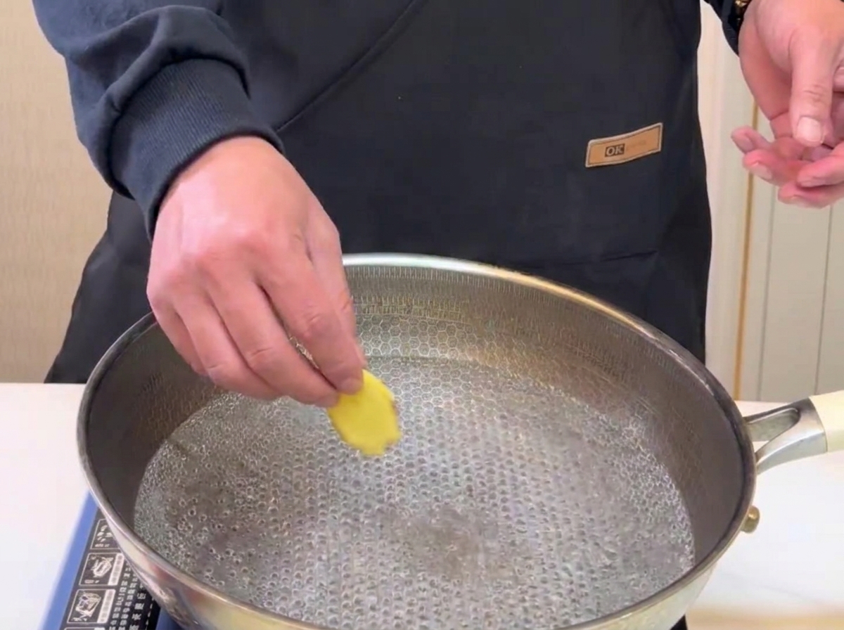Rodajas de jengibre cayendo en una olla con agua hirviendo para escaldar.