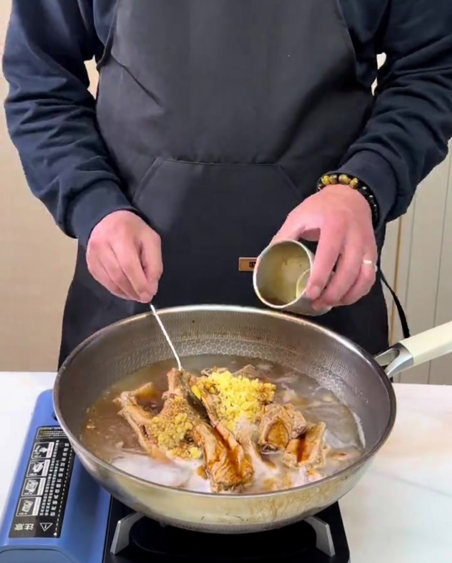Jugo de pera recién preparado vertiéndose en una olla con costillas y sazones.