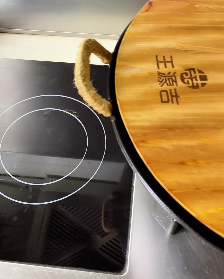 Primer plano de trozos de espinazo de cerdo braseado en un caldo rojo picante y sabroso dentro de un wok grande.