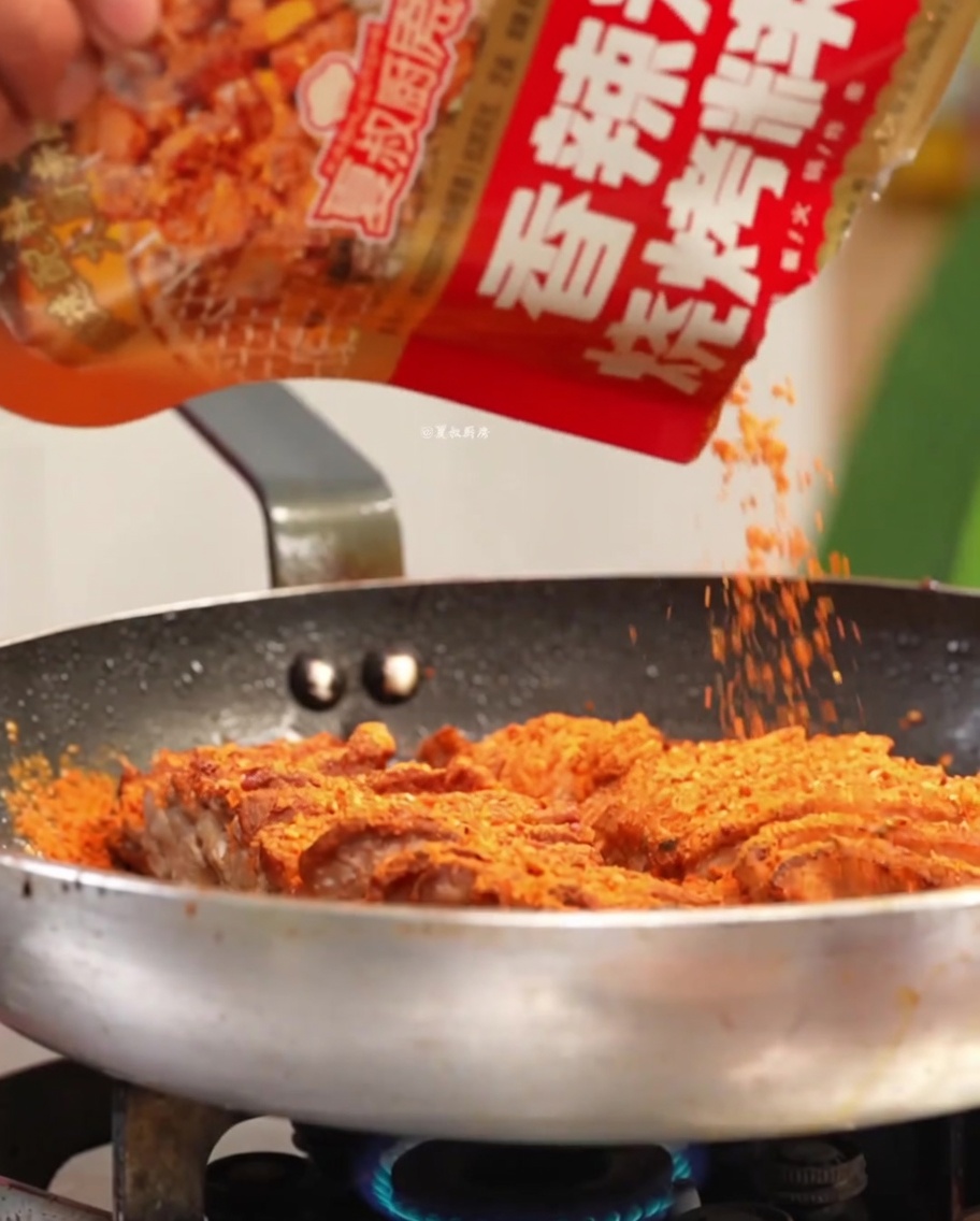 Cerdo siendo sazonado con especias y aromáticos en una sartén caliente.