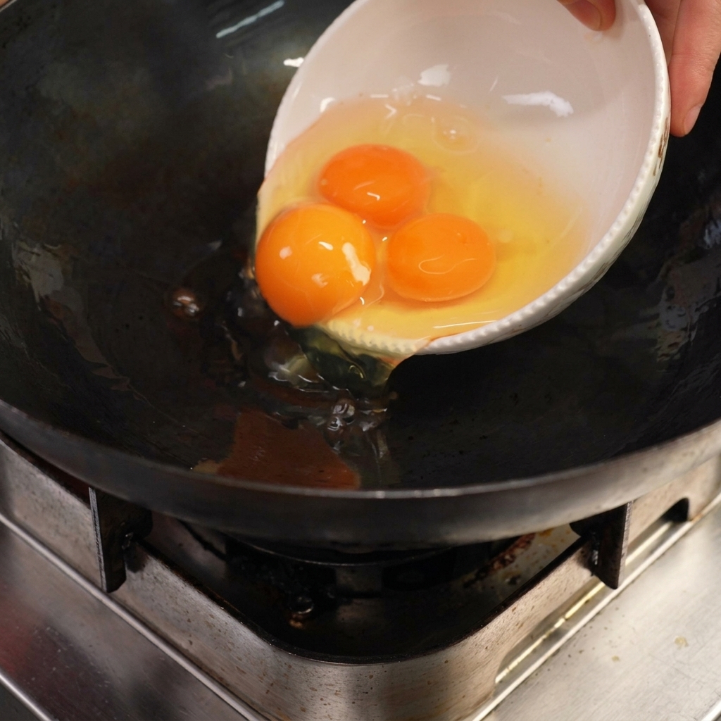 Huevos chisporroteando en un wok con manteca de cerdo caliente.