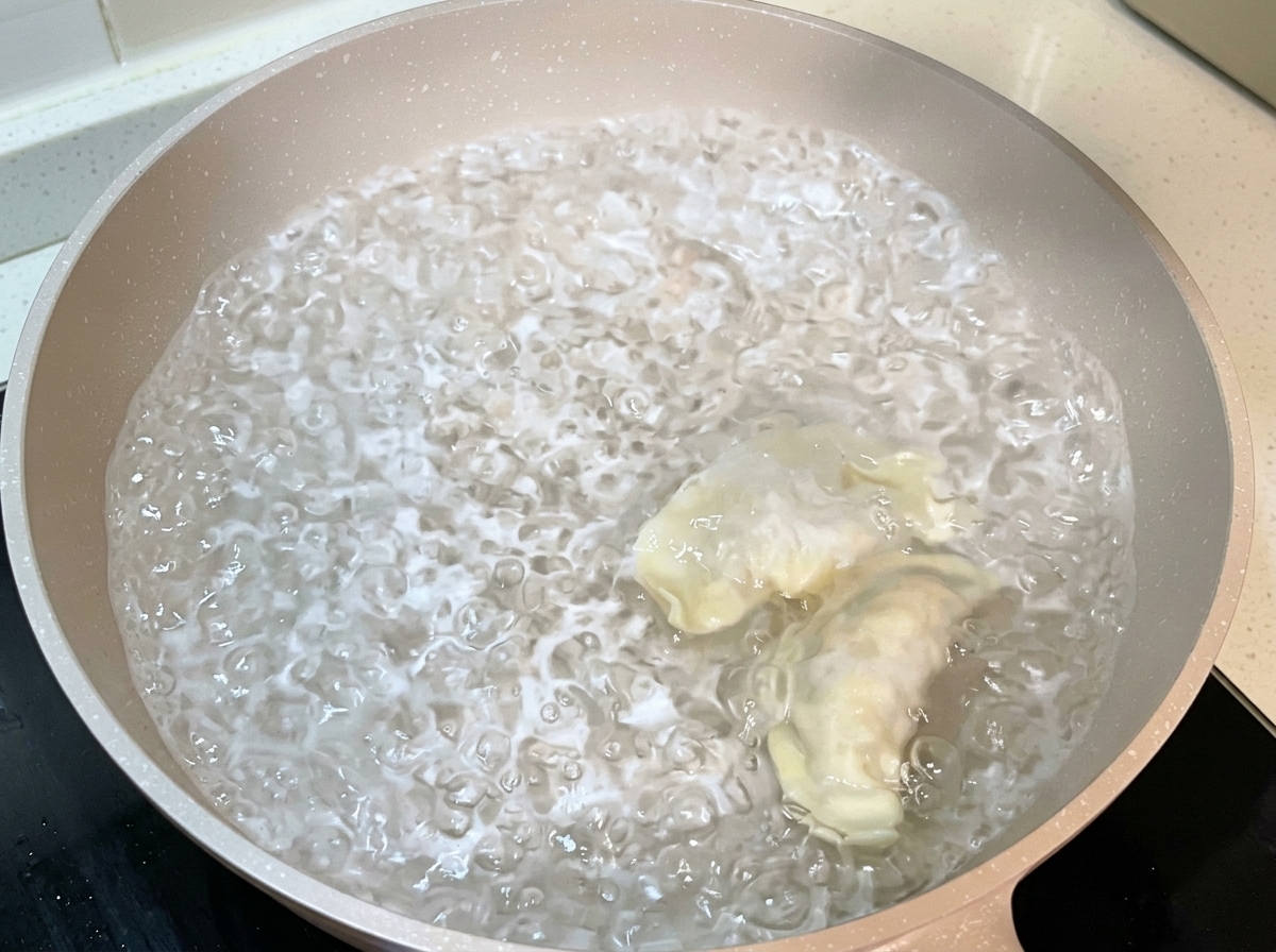 Dumplings armados siendo colocados dentro de una olla grande con agua hirviendo.