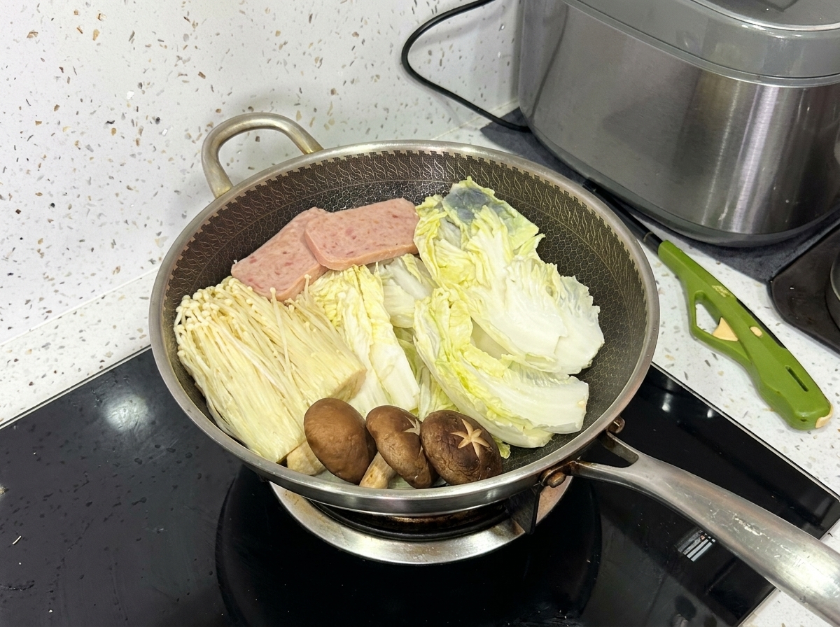 Un wok completamente organizado que contiene col napa, champiñones enoki, hongos shiitake, carne en lata y rodajas de cerdo.