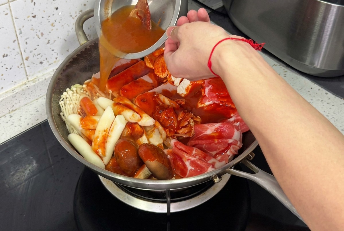 La olla de estofado siendo llenada con agua y cubierta con una tapa de vidrio, lista para hervir a fuego lento.