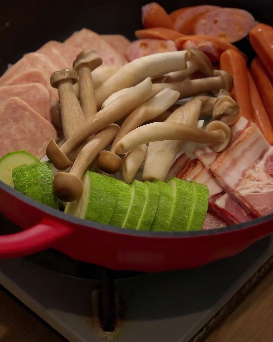 Hongos enoki frescos siendo añadidos en la disposición del hot pot.